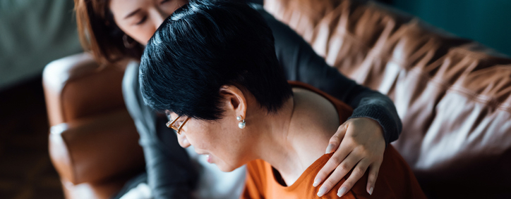 Photo of two women, one consoling the other.